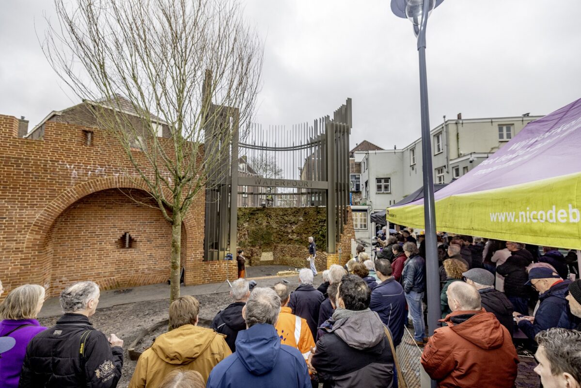 Foto tijdens de opening van het Herman Moerkerkpark waarbij mensen naar de Waterpoort en stadsmuur kijken