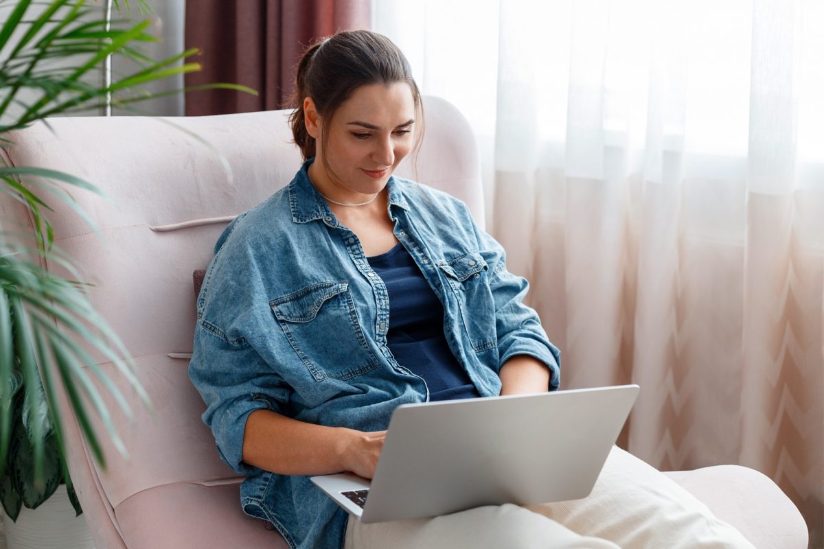 Vrouw zit op schoot met haar laptop en bekijkt iets op haar laptop