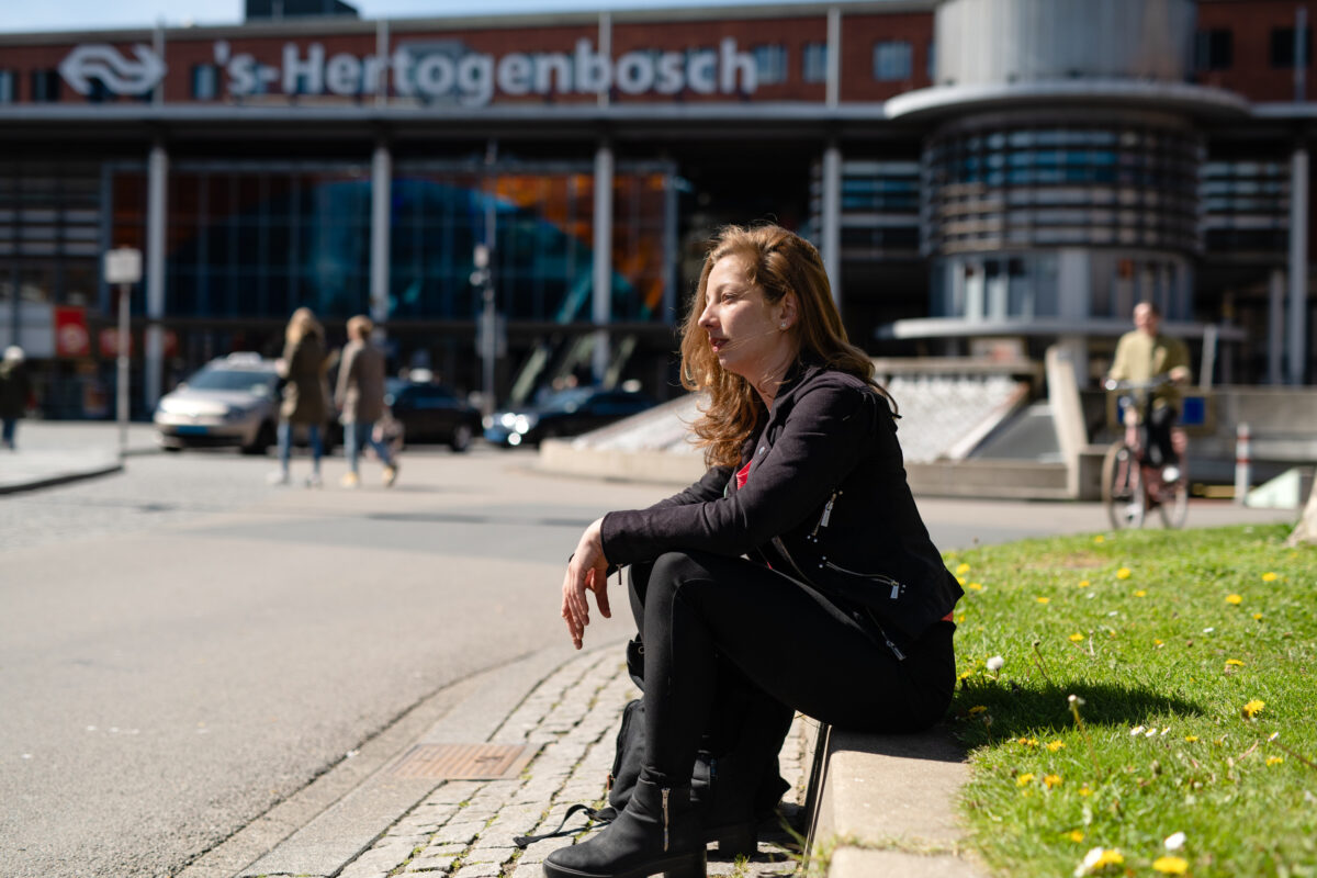 Foto van vrouw die zit op stoep voor centraal station 's-Hertogenbosch